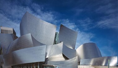 The Walt Disney Concert Hall, home to the Los Angeles Philharmonic, features an acoustically superior auditorium paneled in hardwood. Exterior view of Frank Gehry’s Walt Disney Concert Hall and its oddly curving and angled silvery shapes taken in Los Angeles on a clear, sunny day with a dark blue sky and wispy clouds in the background.