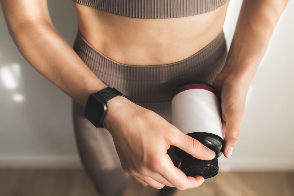 cropped photo of females hands holding and open bottle of vitamins or protein. taking vitamins while posing over white background.