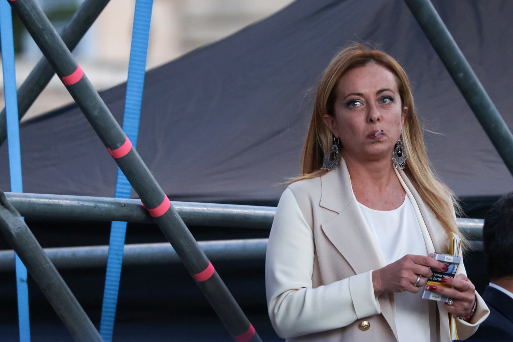 Giorgia Meloni, leader of Brothers of Italy, with a cigarette in her mouth and a pack of cigarettes in her hand, at a general election campaign rally.