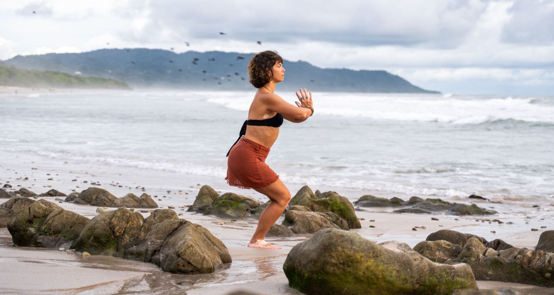 woman on beach doing standing yoga