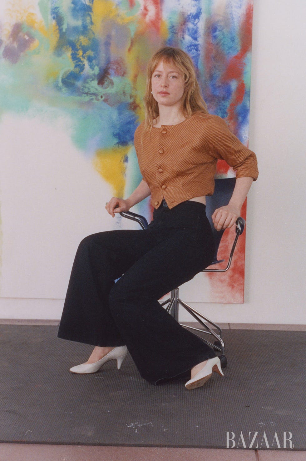 model seated on a chair against a colorful backdrop
