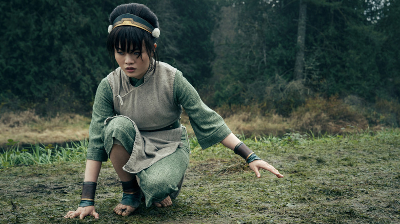 Toph kneeling on the ground, feeling the vibrations in the earth in Netflix's live-action Avatar: The Last Airbender series