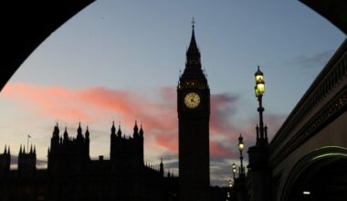 Elizabeth Tower and the Houses of Parliament silhouetted at dusk, with a glowing clock face and pink clouds in the sky.
