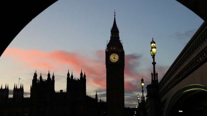 Elizabeth Tower and the Houses of Parliament silhouetted at dusk, with a glowing clock face and pink clouds in the sky.