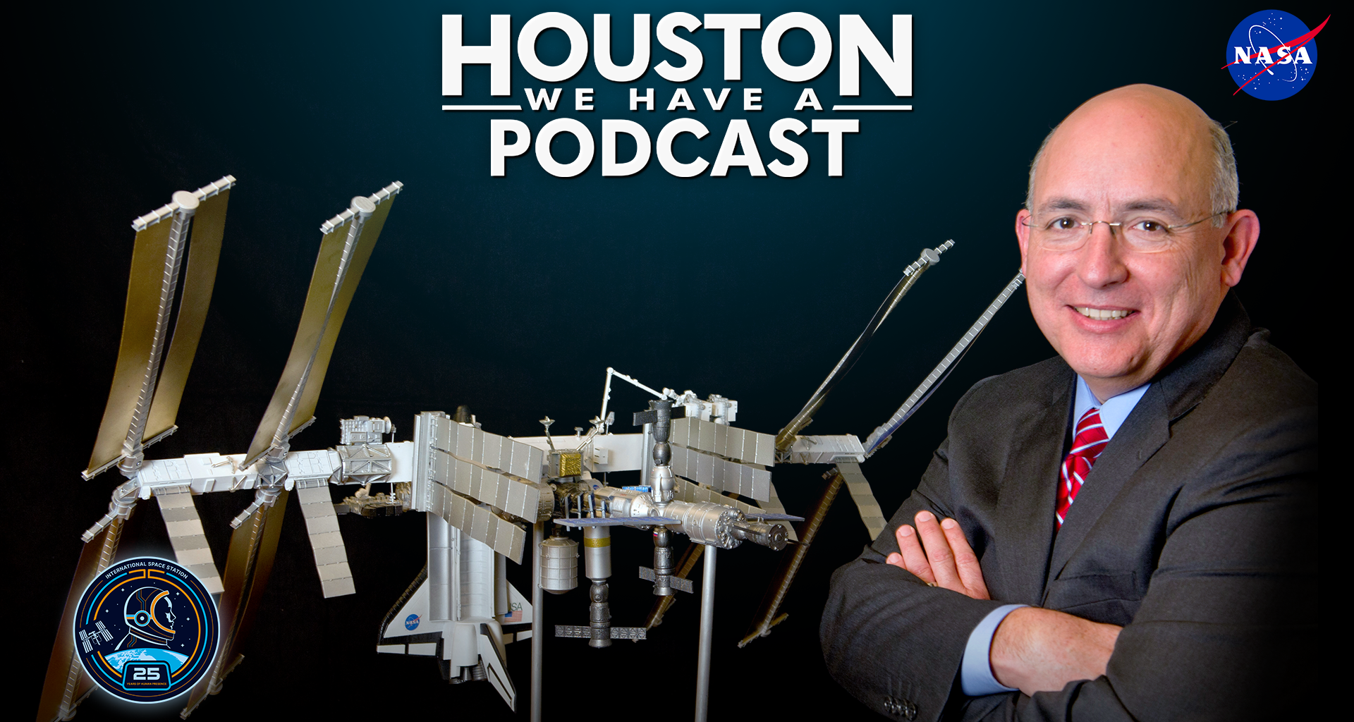 HWHAP Ep. 405. Mike Suffredini crosses his arms in front of a model of the International Space Station.