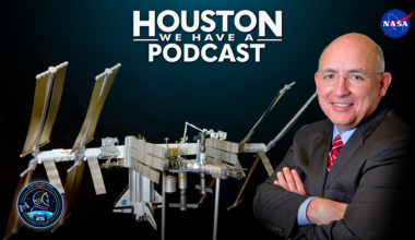 HWHAP Ep. 405. Mike Suffredini crosses his arms in front of a model of the International Space Station.