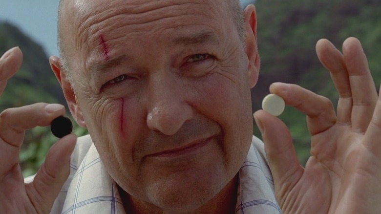 John Locke holding up black and white stones with a scar on his face on Lost