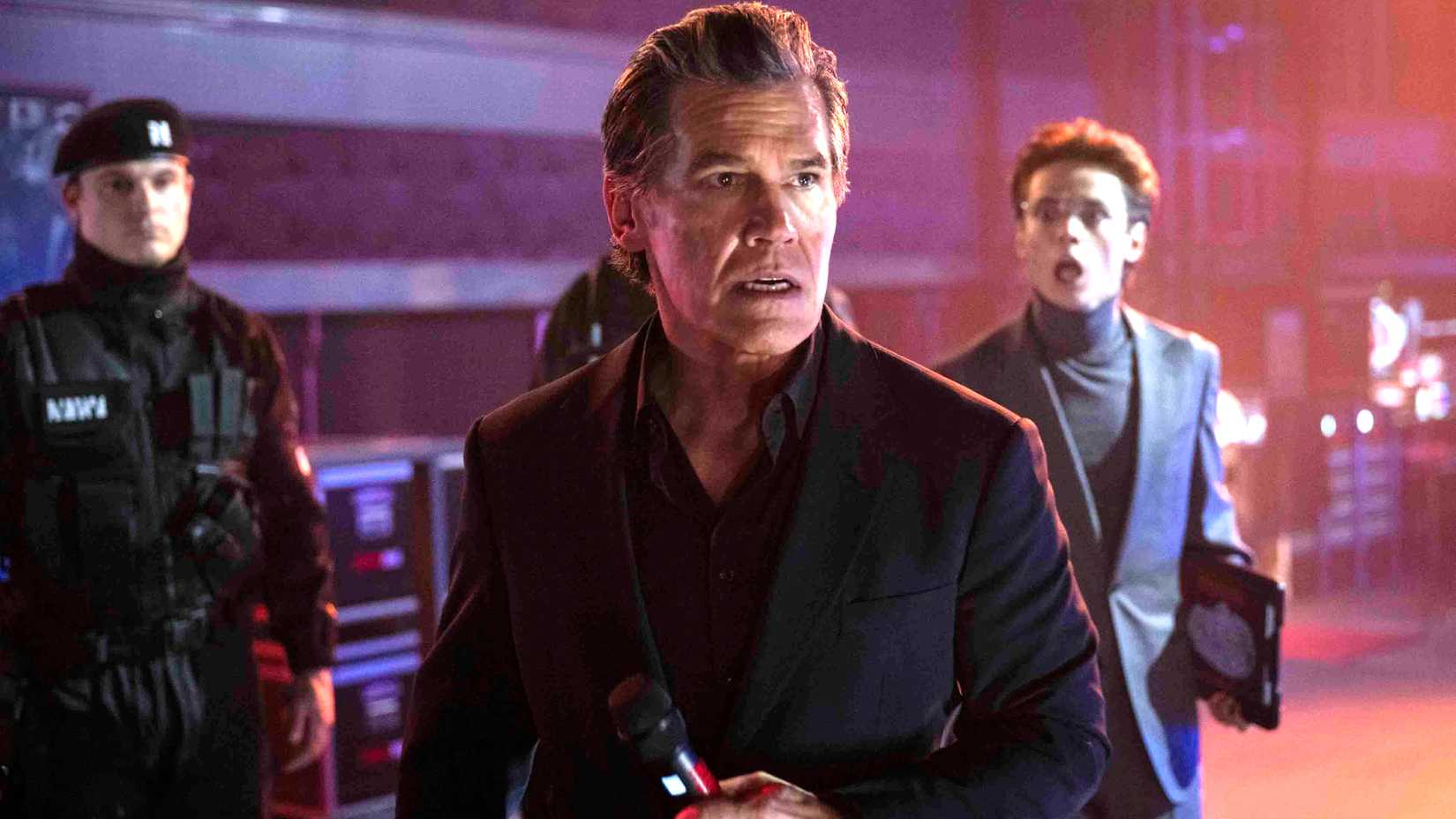 Josh Brolin as Dan Killian looking worried while holding a microphone in The Running Man