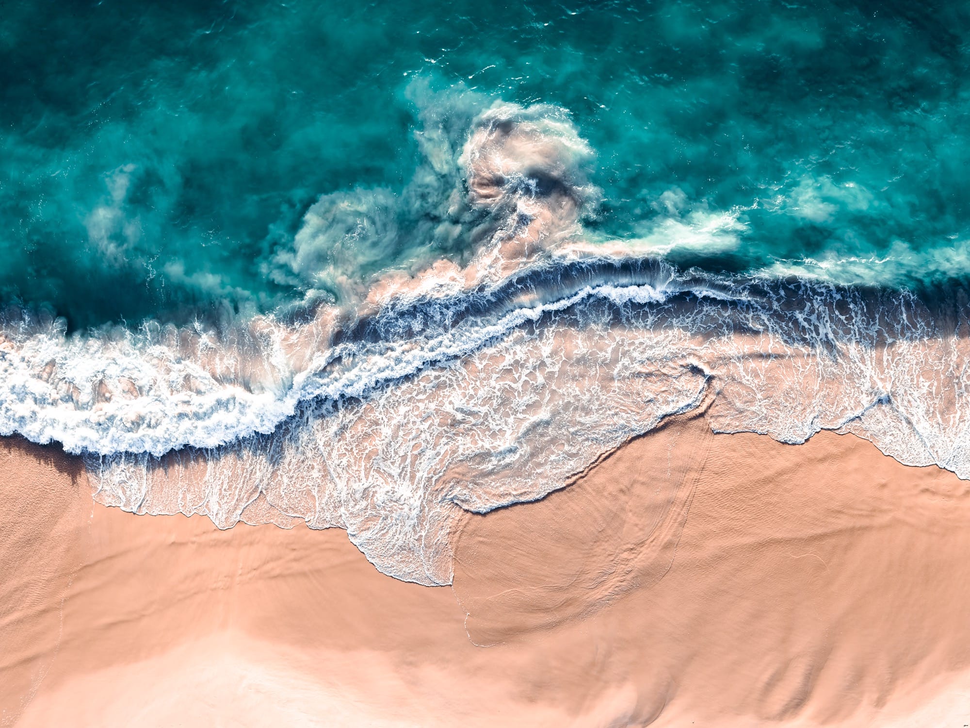 An aerial view of crashing waves shot at a vertical angle by Kevin Krautgartner