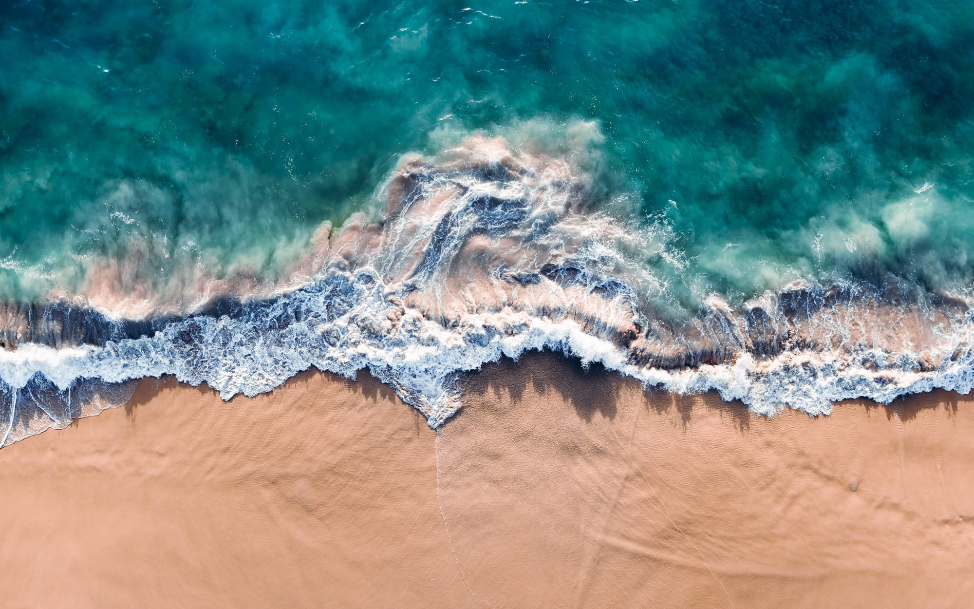 An aerial view of crashing waves shot at a vertical angle by Kevin Krautgartner