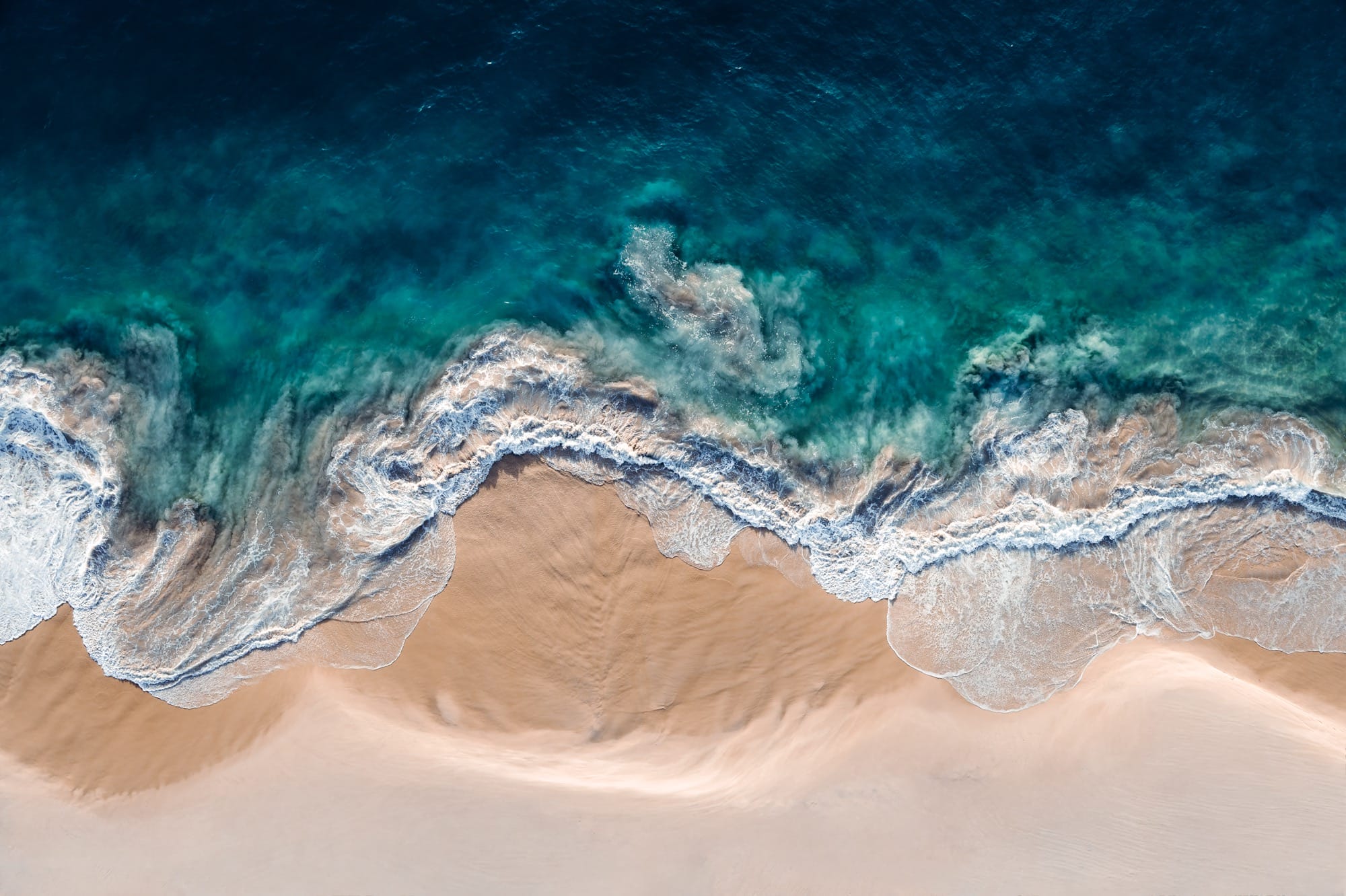 An aerial view of crashing waves shot at a vertical angle by Kevin Krautgartner