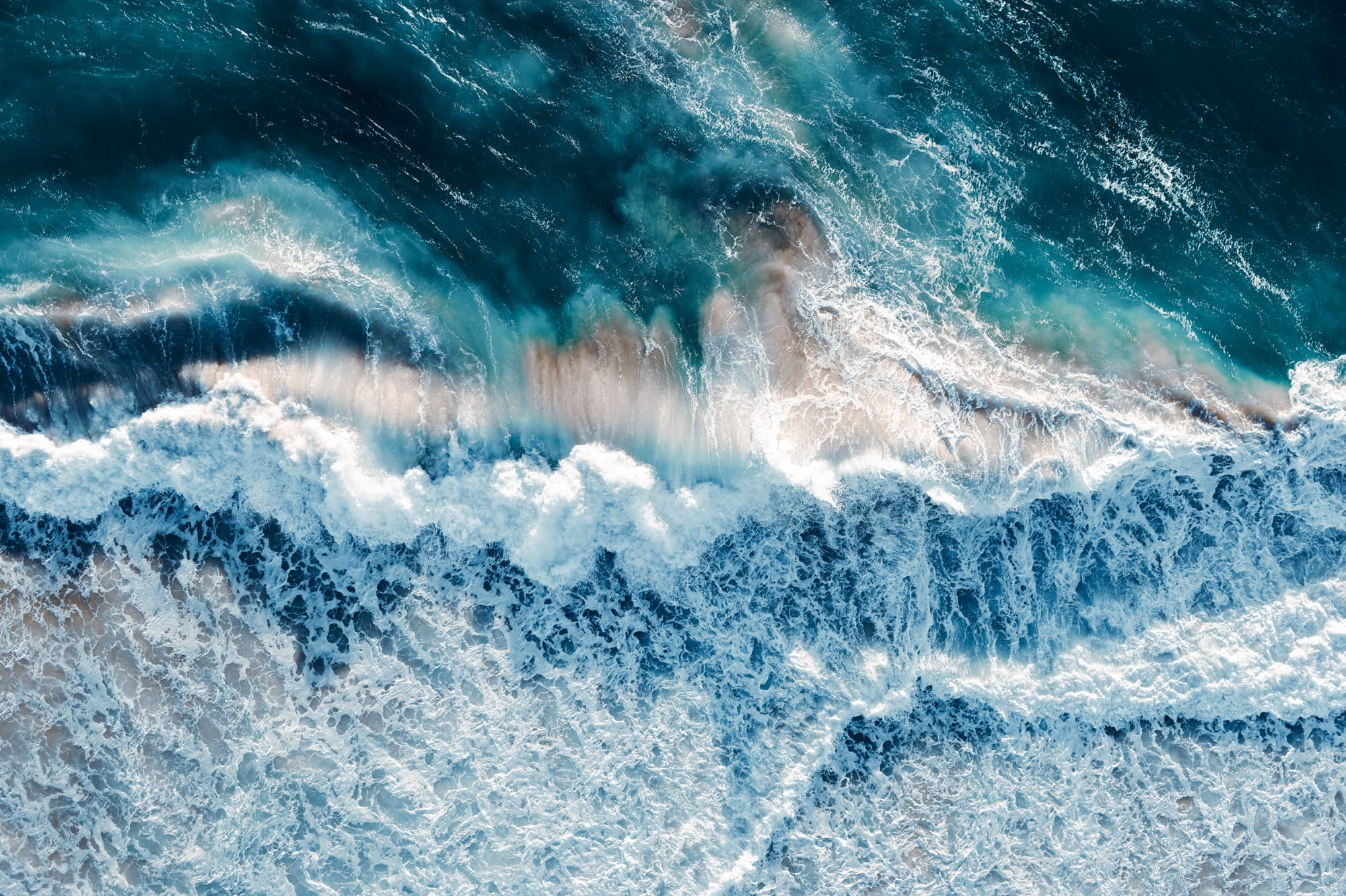 An aerial view of crashing waves shot at a vertical angle by Kevin Krautgartner