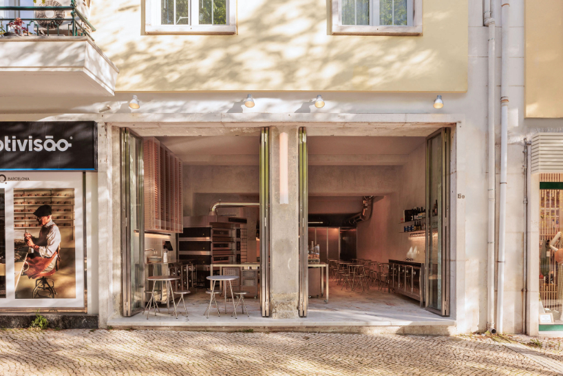 reflective steel interiors and open facade bring lisbon’s street activity into pizza restaurant