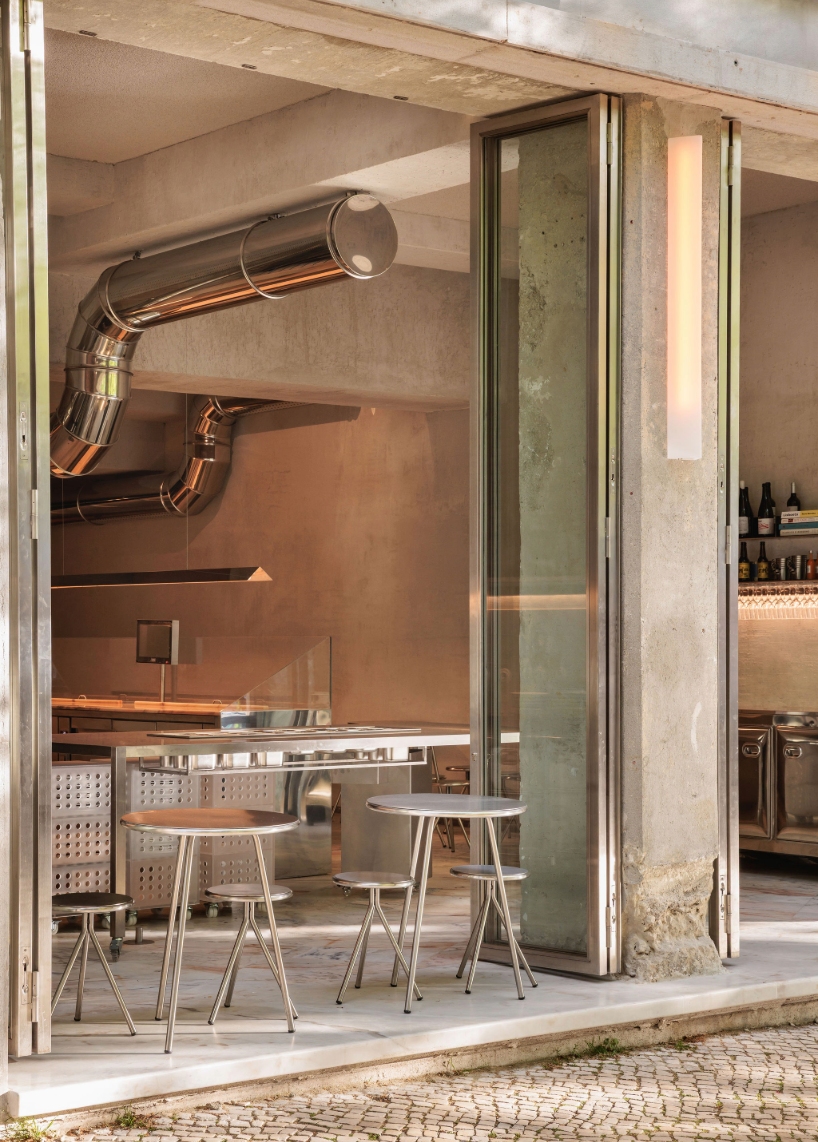 reflective steel interiors and open facade bring lisbon’s street activity into pizza restaurant