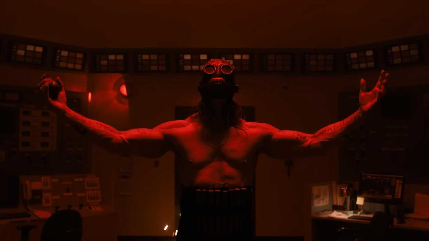 Man in a mask with his arms raised in Psycho Killer