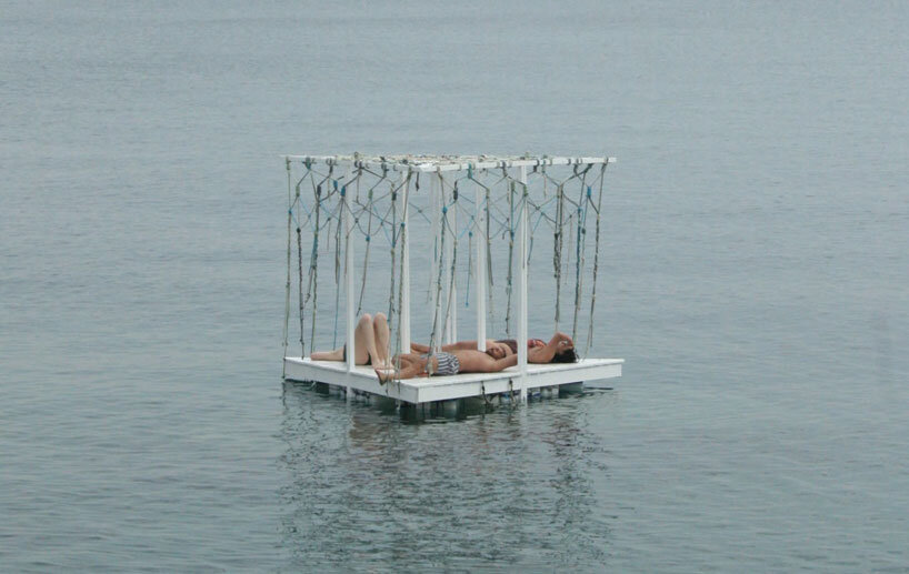 triangular wooden pavilion floats on reused plastic gallons along croatia’s coasts