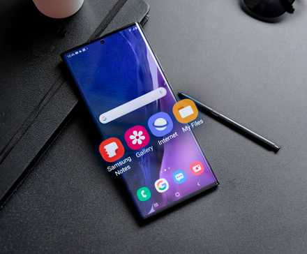 Samsung smartphone with some Stock Apps sticking out of the screen and the S Pen next to it