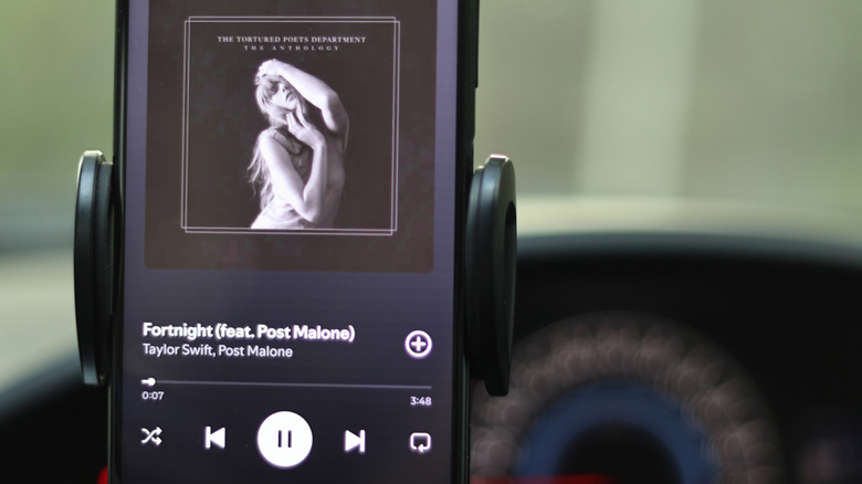 A Taylor Swift album playing on Spotify on a phone in a car mount.