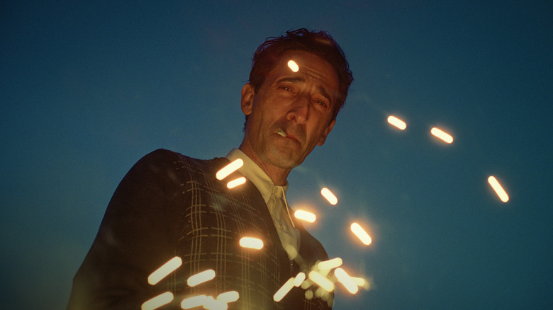 Adrien Brody as László Tóth, looking down at sparks in The Brutalist