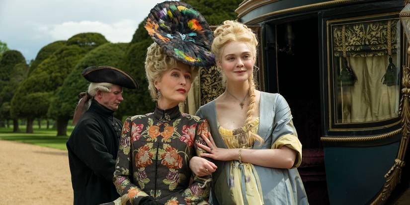 Gillian Anderson and Elle Fanning in fancy dresses outside next to a carriage, smiling in The Great.