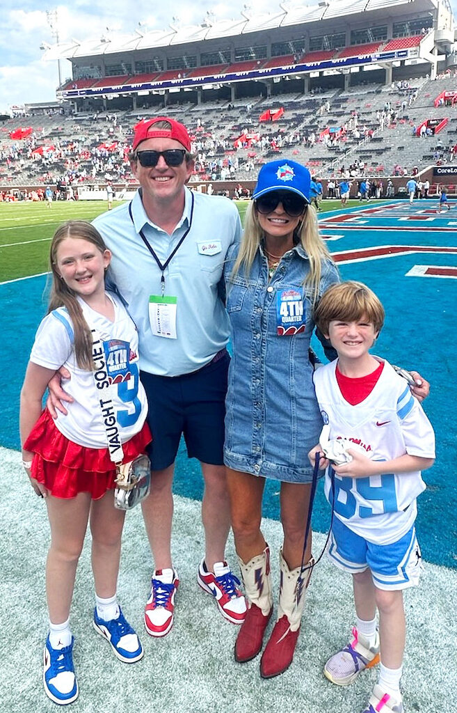 A family stands on the field in a nearly empty football stadium.