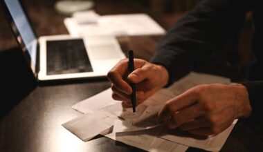 Hands reviewing paperwork and receipts beside a laptop on a desk