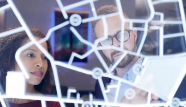 A team of two people looking at a digital layout on a glass wall, trying to analyze it.
