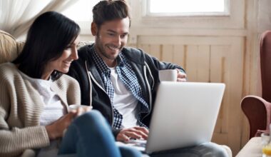 Two investors look at something on a laptop at home.