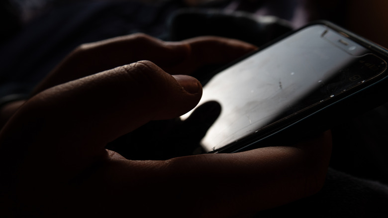 Someone holding an iPhone with their right thumb hovering over the screen