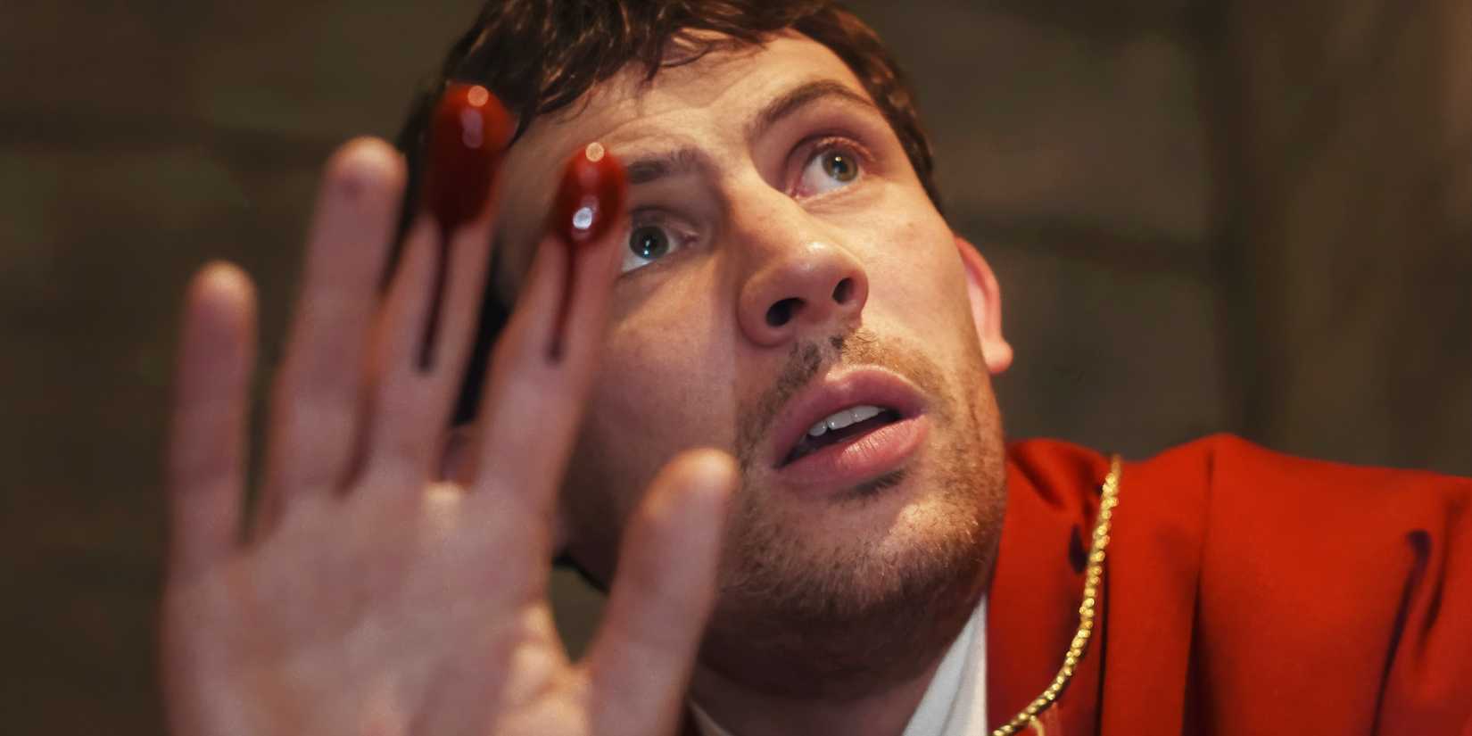 Josh O'Connor as Jud holding up bloody fingers in Wake Up Dead Man.