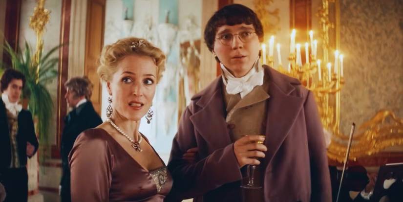 Gillian Anderson and Paul Dano standing in front of a candlebra at a fancy party in War and Peace.