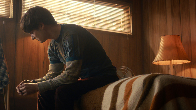 Will (Noah Schnapp) sits on a bed looking forlorn in Stranger Things Season 5