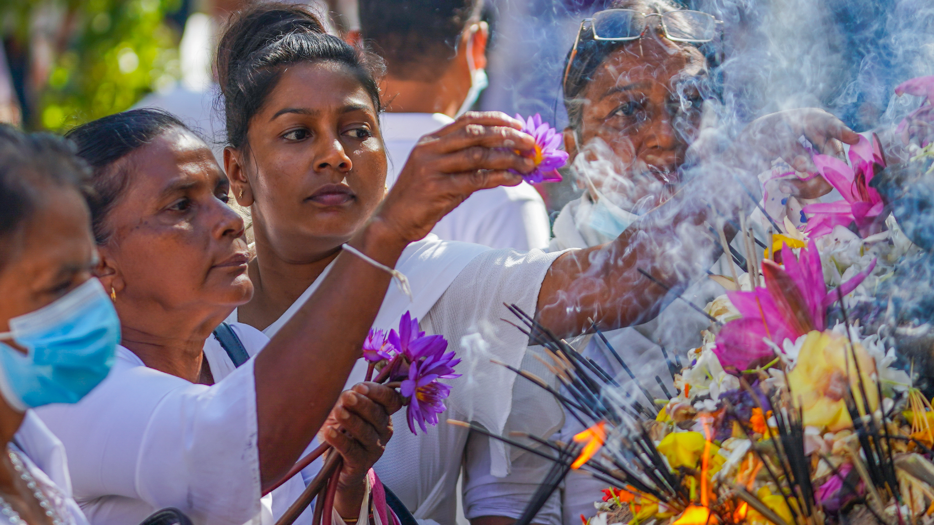 People are shown burning incense and arranging flowers during a religious festival.