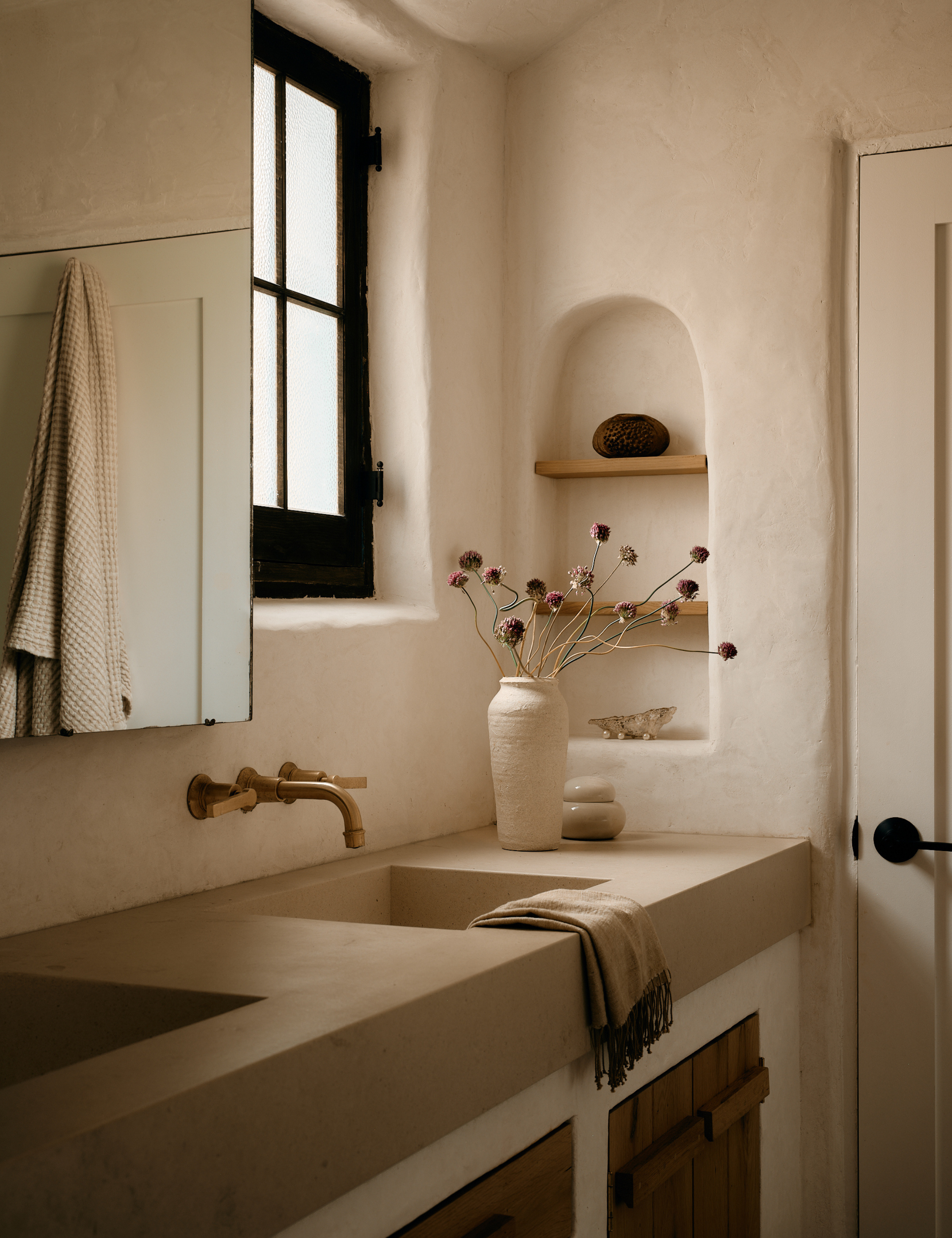 Calming California bathroom that features plaster walls, an arched recessed wall niche, and an original mirrored medicine cabinet