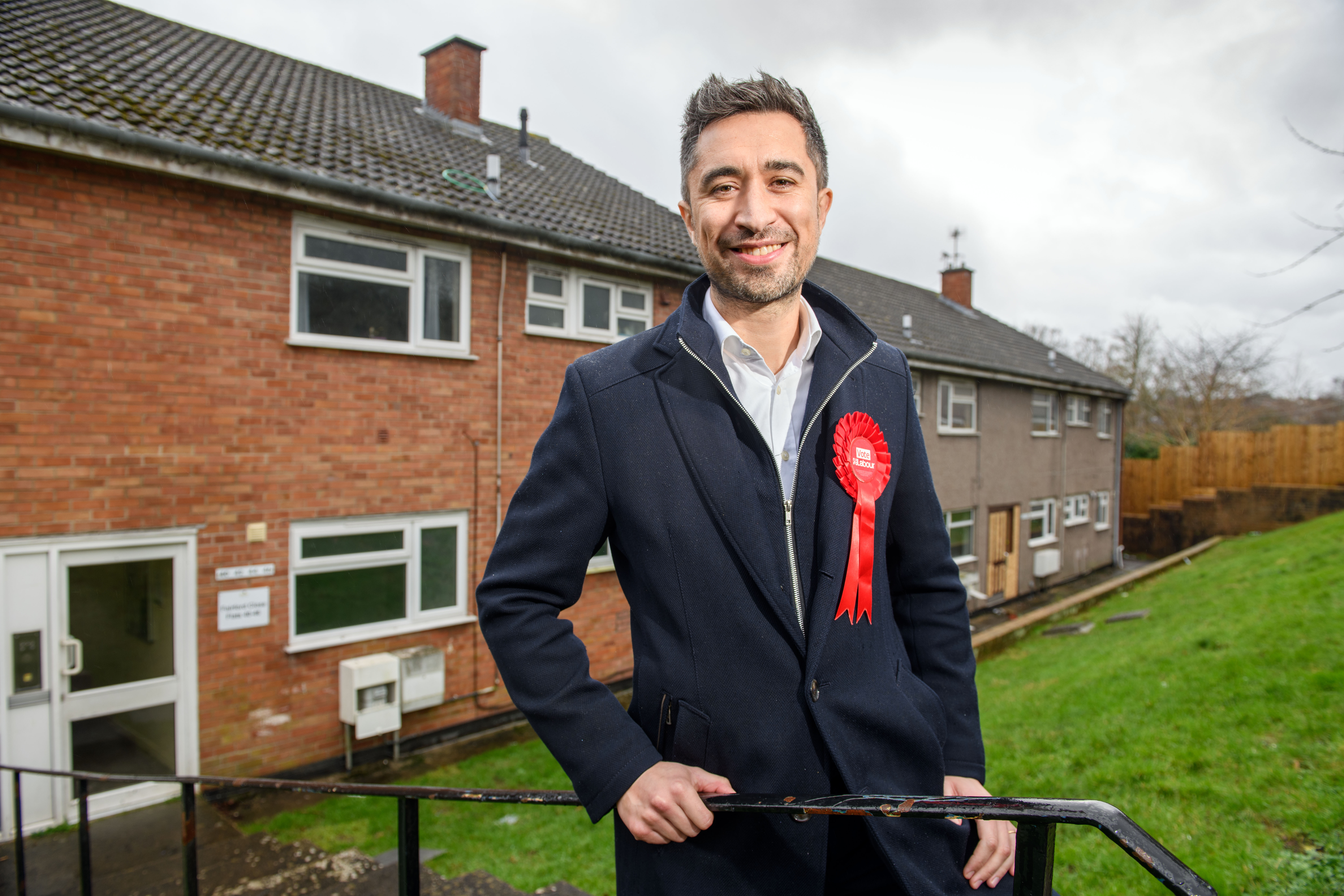 Labour candidate Damien Egan stands in front of a brick building where he grew up.