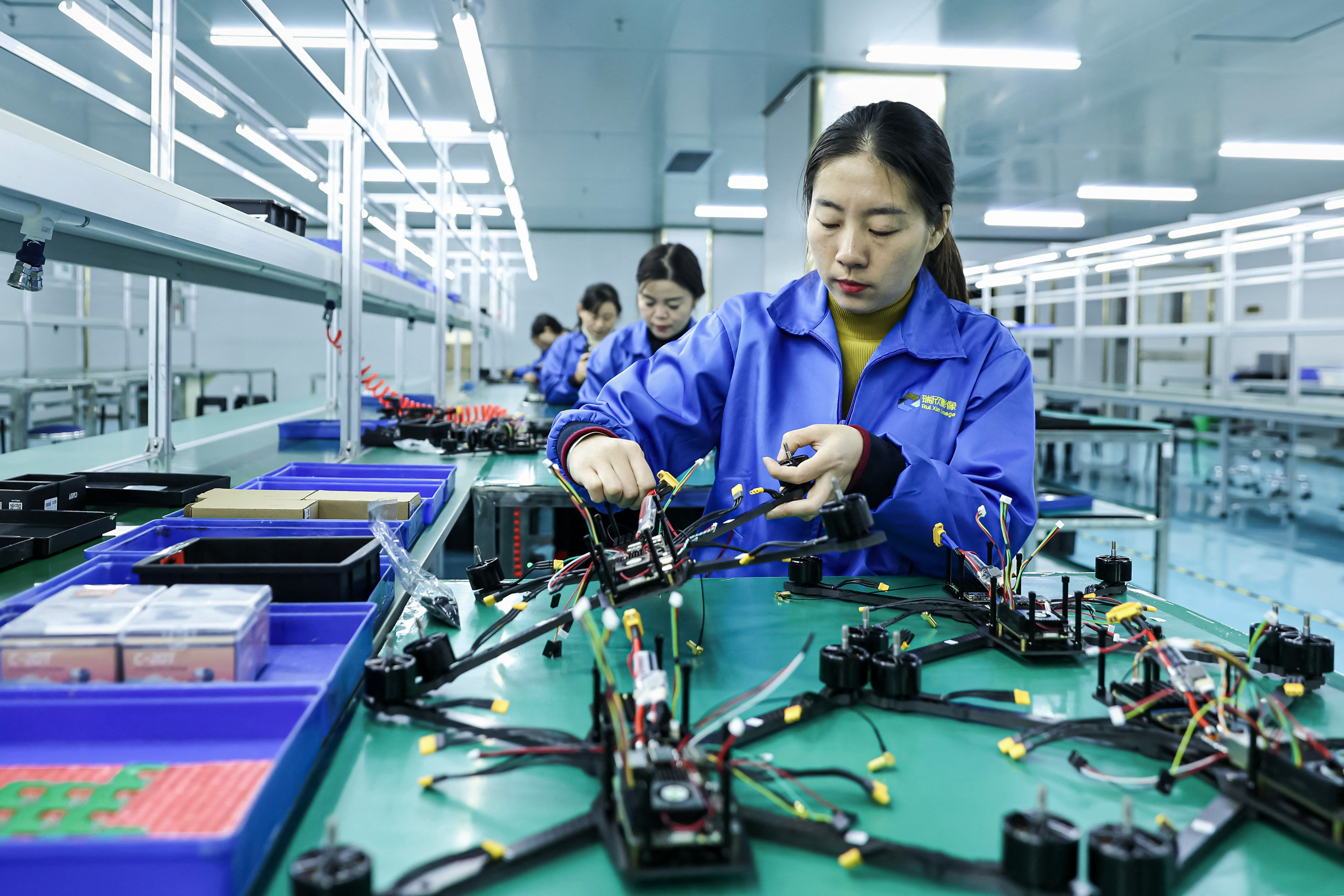 Employees assemble drones on a production line in a factory.