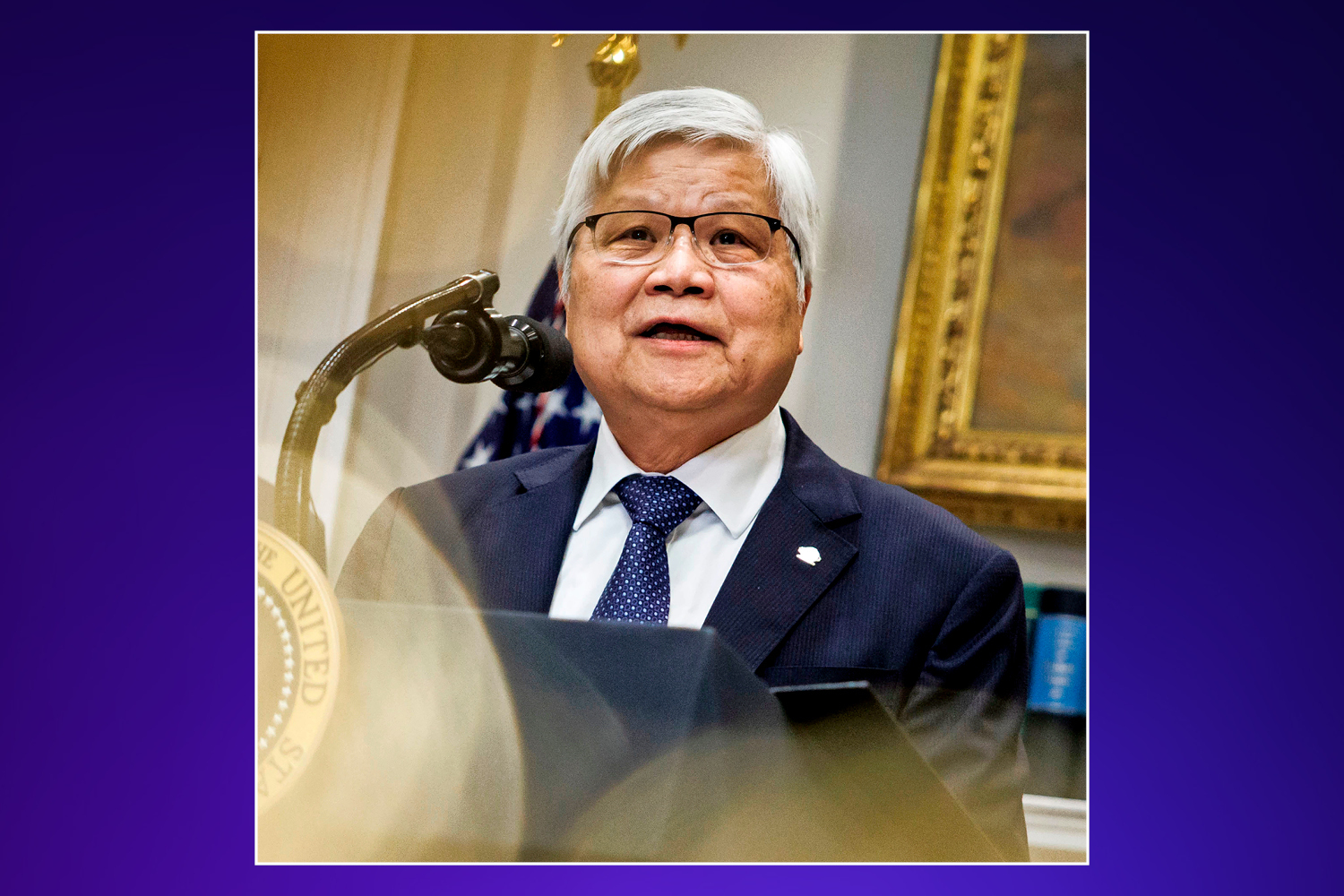 A man with gray hair and glasses speaking at a podium.