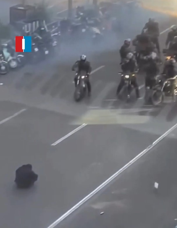 A protester sitting in the road in Tehran faces off against security forces on motorbikes