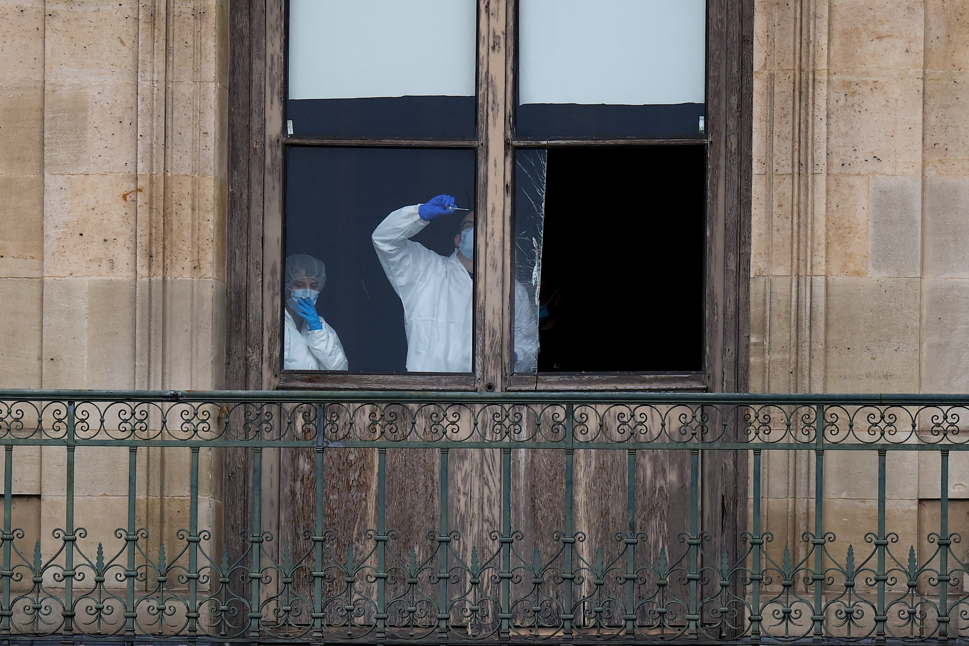 Forensic team members inspect a broken window at the Louvre Museum after a jewelry robbery.