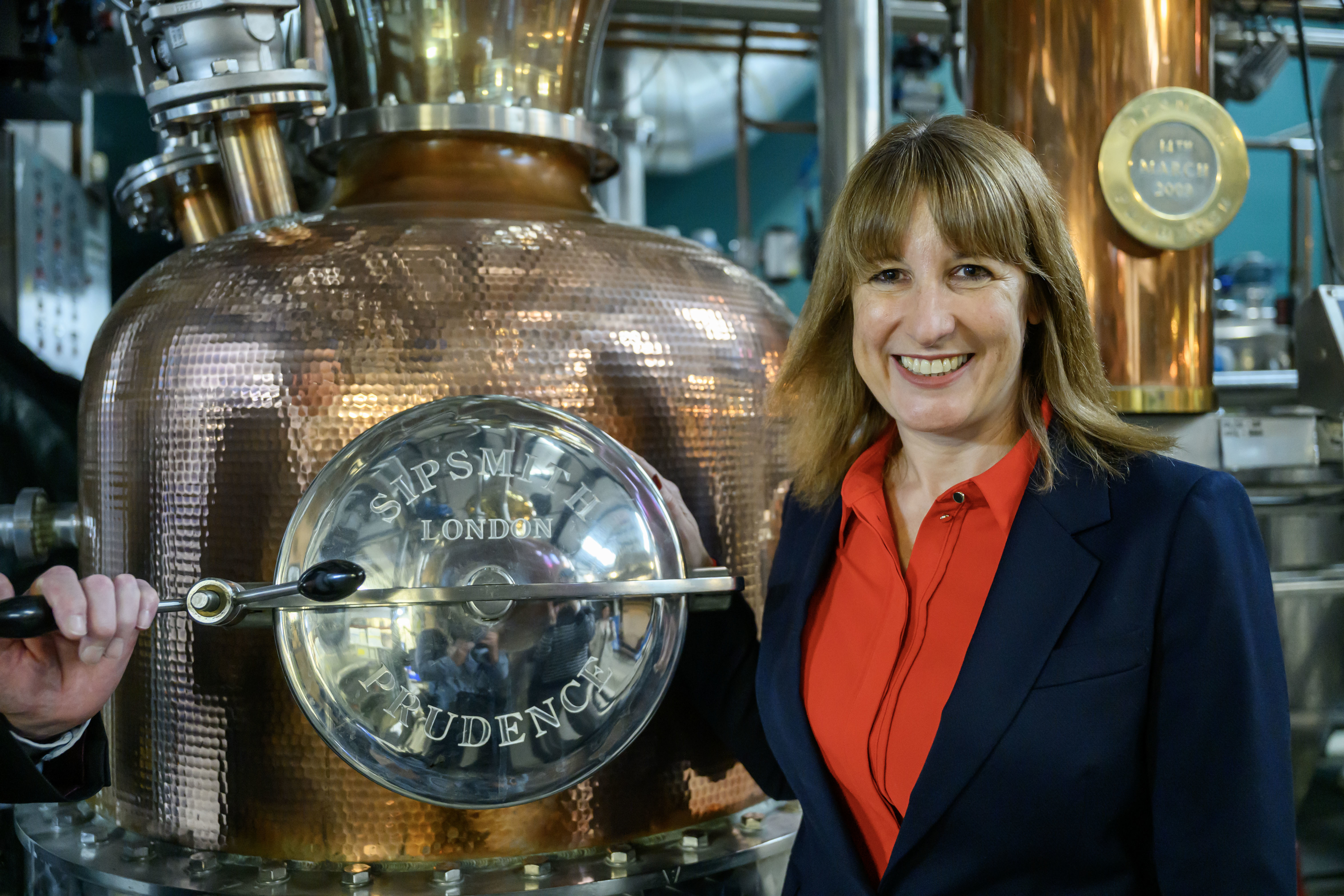 Rachel Reeves stands beside a copper still named Prudence at Sipsmith Distillery.