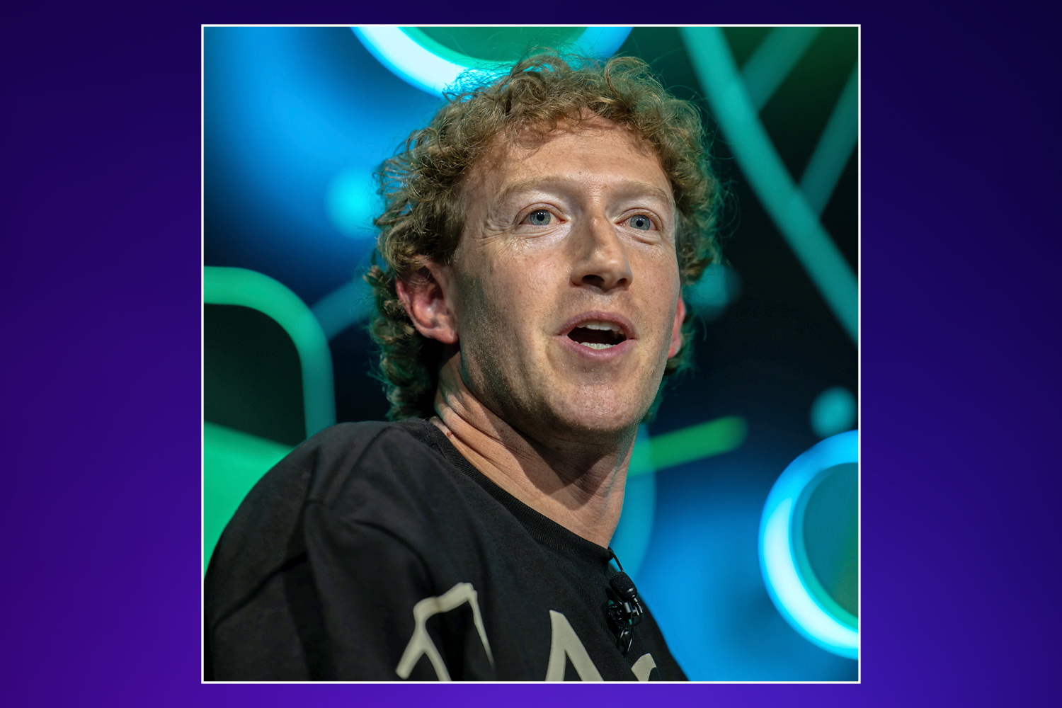 Mark Zuckerberg speaking with his mouth slightly open, wearing a black t-shirt, against a background of blue and green lights.