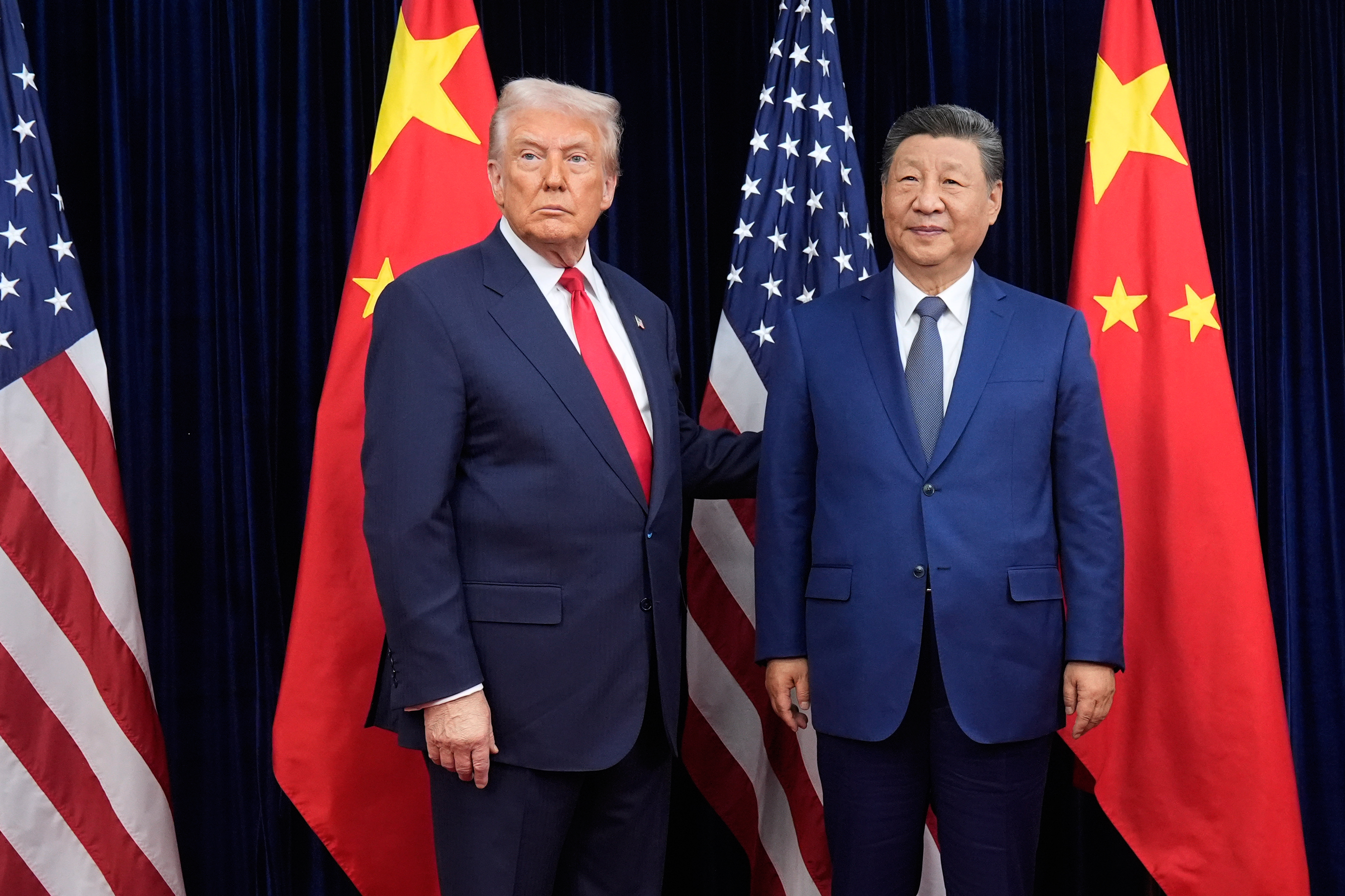 President Donald Trump and Chinese President Xi Jinping pose in front of US and Chinese flags.