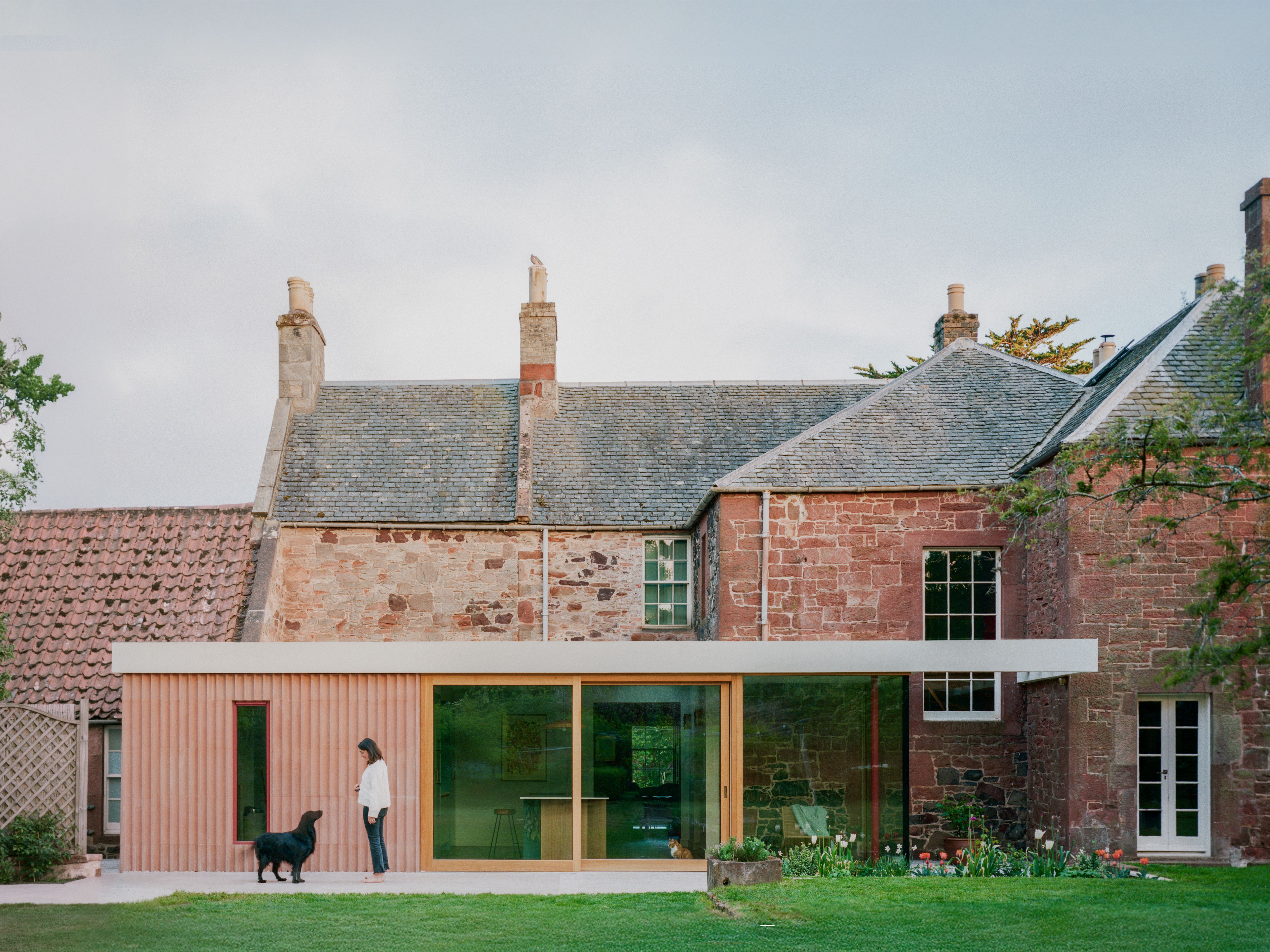 Whitberry House, with a woman and dog standing outside a modern extension with a large glass door.