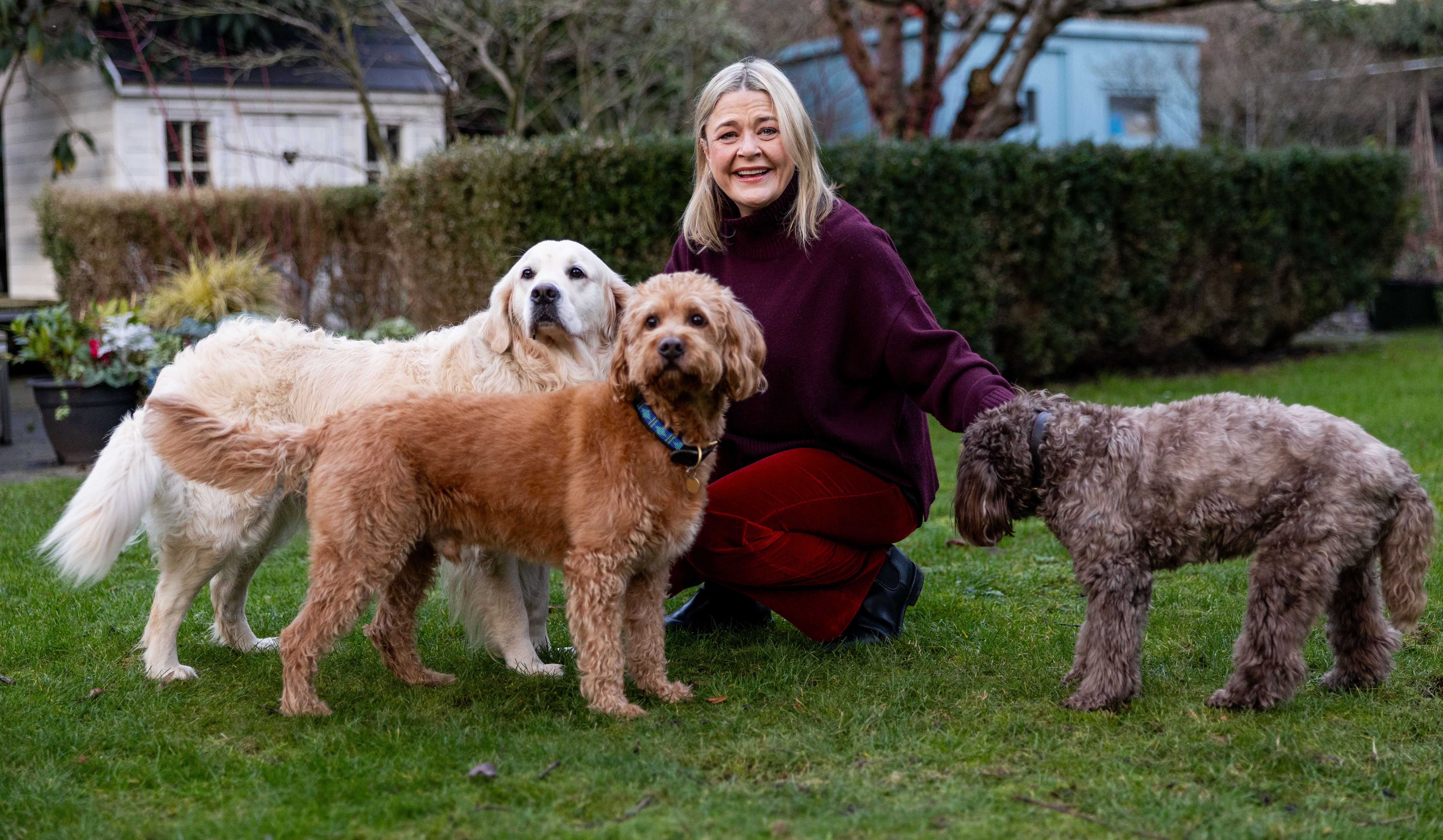 Harriet Tyce with her dogs Coco, Cooper, and Isla in her garden.