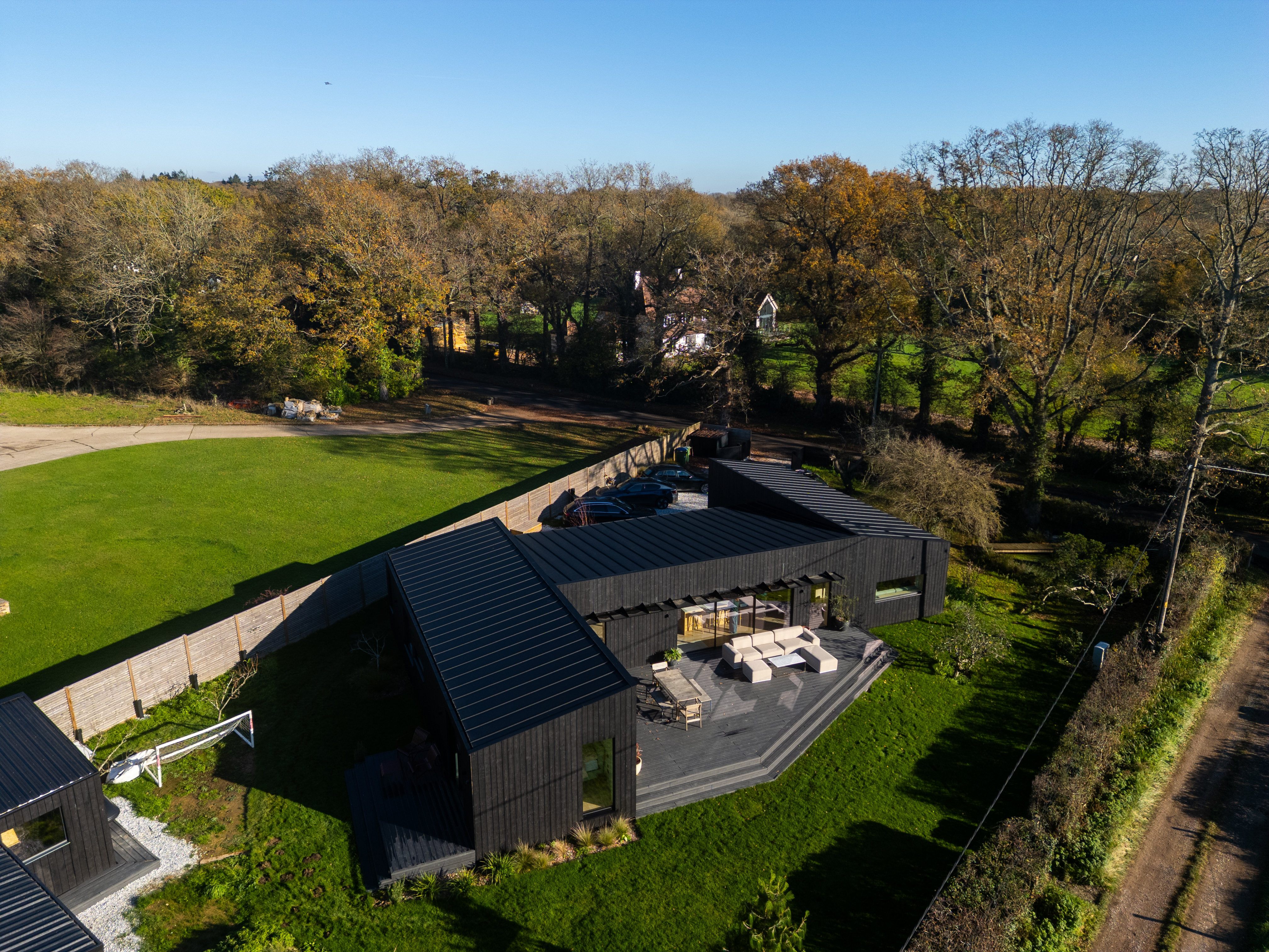 Aerial view of Peter and Aey Aspdin's home in West Sussex, a modern black house with a large outdoor patio and surrounding greenery.