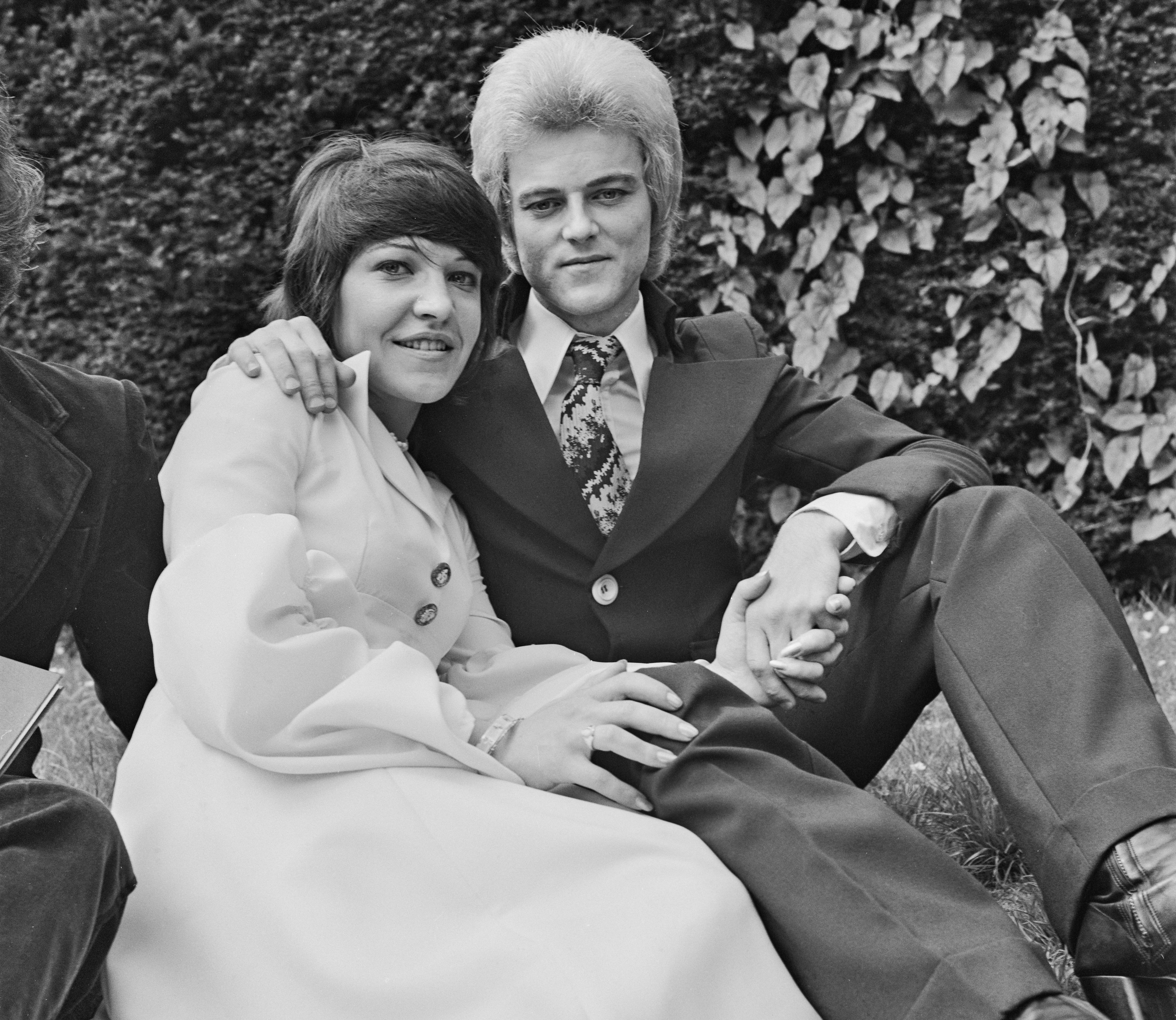 Mick Woodmansey of David Bowie's band and June Harrison sitting on the grass at their wedding.