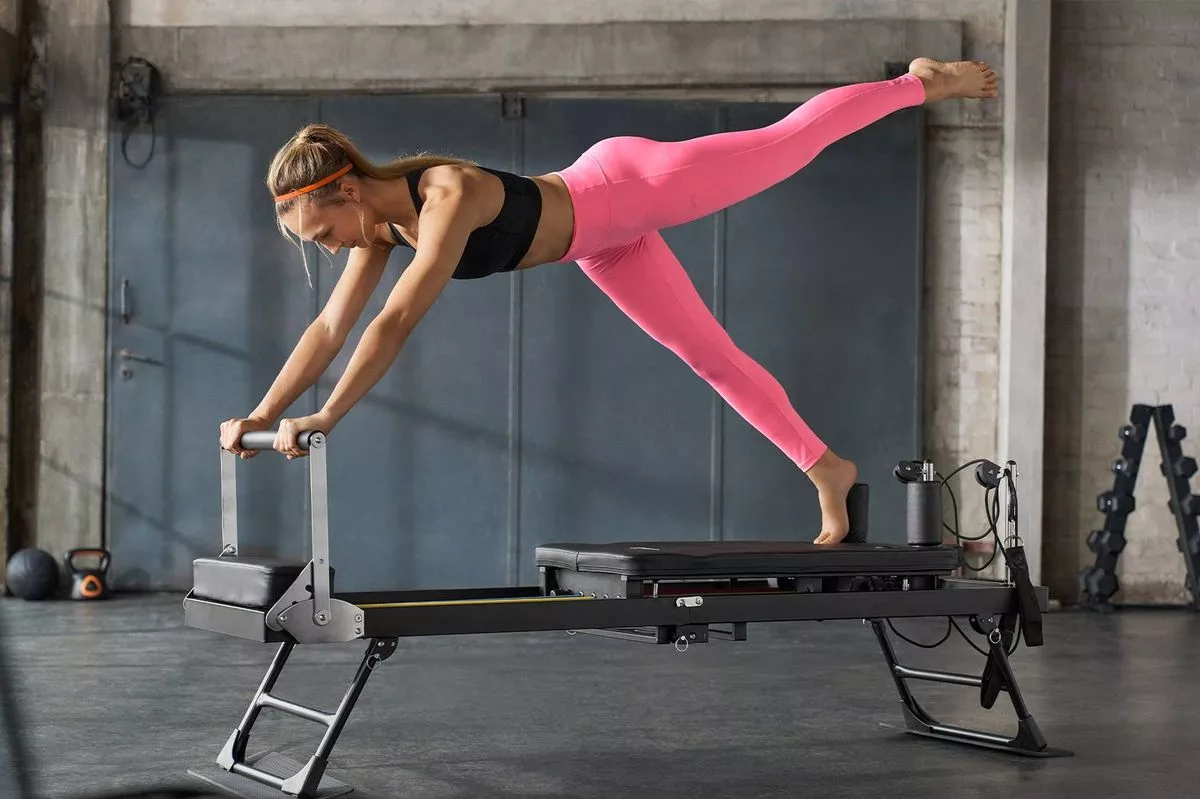 A woman using a Reformer Pilates machine 