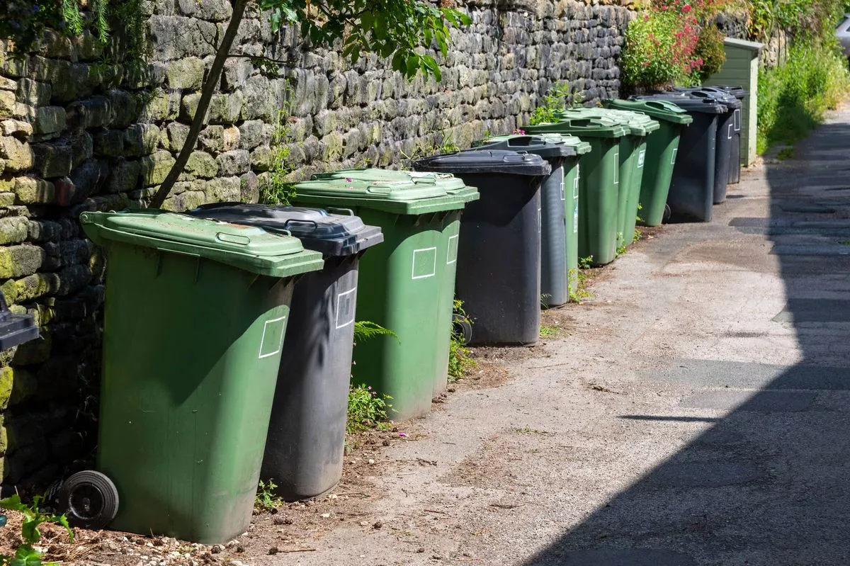 Refuse bins lined up opposite a terrace of cottages in Hinchliffe Mill village near Holmfirth, Northern England.
