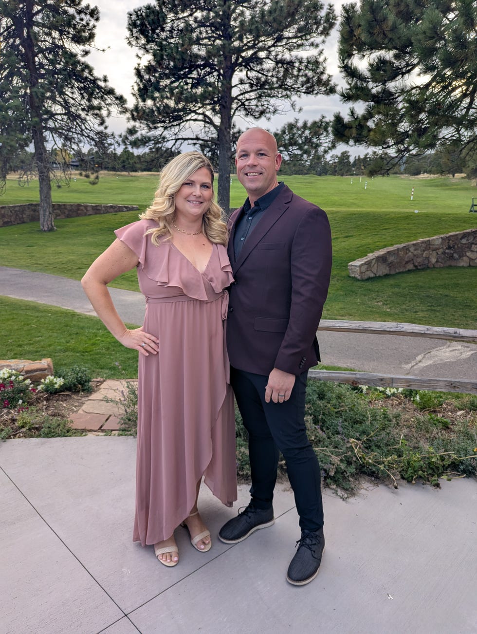 a couple posing together outdoors at a venue with greenery in the background