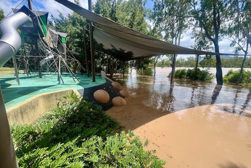 Brown river surrounds a riverside playground